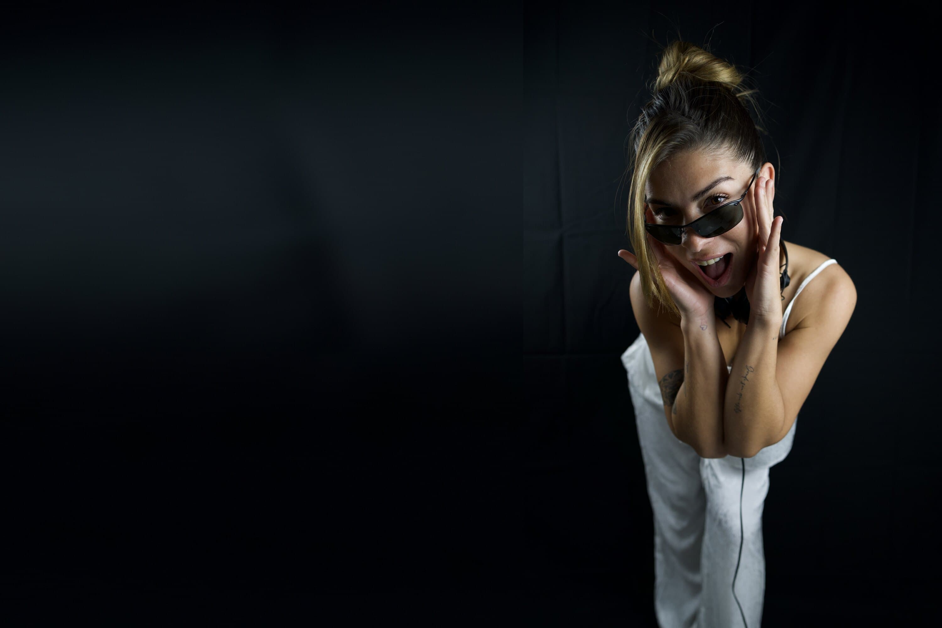 Maru Bravo, studio portrait in sunglasses, hands framing her face